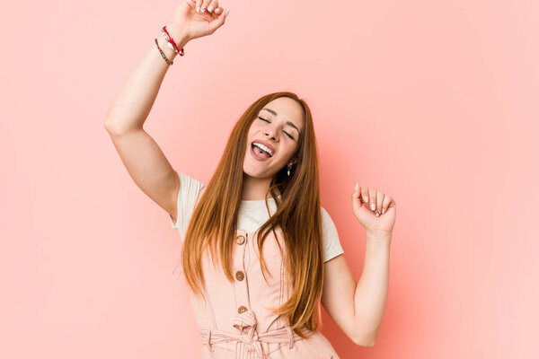 Молодая рыжая женщина с веснушками празднует особый день, прыгает и поднимает руки с энергией
.