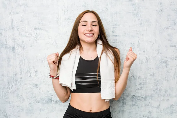 Young fitness woman raising fist, feeling happy and successful. Victory concept.