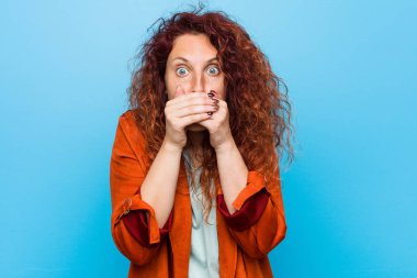 Young redhead elegant woman shocked covering mouth with hands.