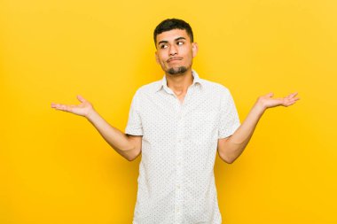 Genç İspanyol adam bir kopyasını alanı tutmak için karışık ve şüpheli omuzsitme omuzlar.