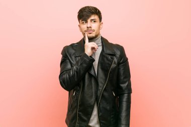 Şüpheli ve şüpheci ifade ile yana bakan bir deri ceket giyen genç İspanyol adam.