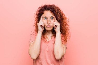 Genç doğal ve otantik kızıl saçlı kadın bir görev üzerinde duruldu, baş işaret eden işaret parmakları tutmak.