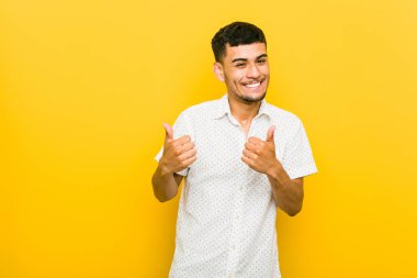 Genç İspanyol adam, gülümseyerek ve kendinden emin, her iki başparmak yükselterek.