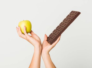 Aplle veya çikolata tablet arasında seçim genç İspanyol kadının ellerini yakın