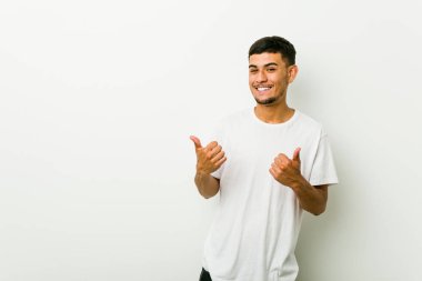 Genç İspanyol adam, gülümseyerek ve kendinden emin, her iki başparmak yükselterek.