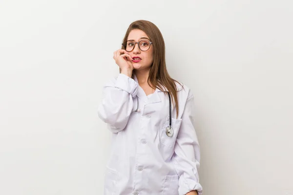 Jonge Dokter Vrouw Tegen Een Witte Muur Bijten Vingernagels Nerveus — Stockfoto