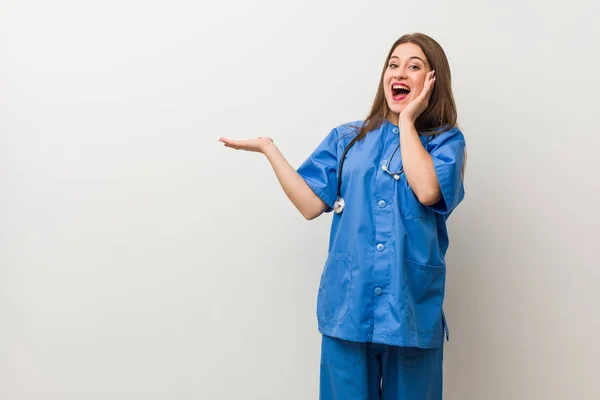 Jonge Verpleegster Vrouw Tegen Een Witte Muur Houdt Kopie Ruimte — Stockfoto
