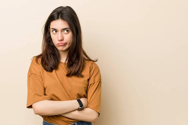 Junge Brünette Frau Vor Beigem Hintergrund Sieht Mit Sarkastischem Gesichtsausdruck — Stockfoto