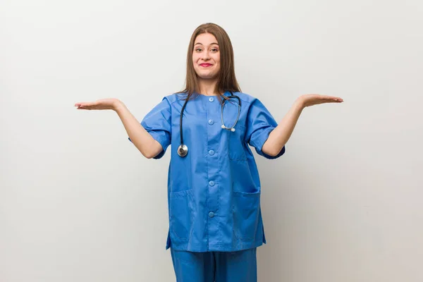 Молодая Медсестра Прислонившись Белой Стене Взвешивает Руками Чувствует Себя Счастливой — стоковое фото