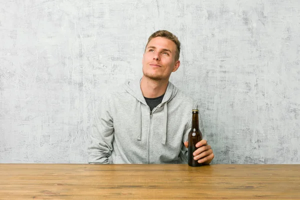 Jovem Bebendo Uma Cerveja Uma Mesa Sonhando Alcançar Objetivos Propósitos — Fotografia de Stock
