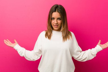 Bir duvara karşı genç otantik karizmatik gerçek insanlar kadın hoş bir ifade gösteren.