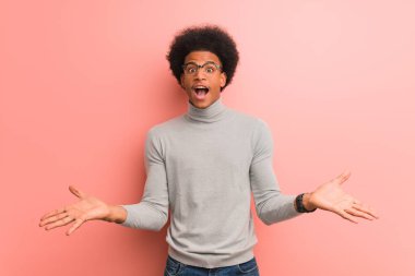 Bir zafer ya da başarı kutlayan pembe bir duvar üzerinde genç afro-amerikan adam