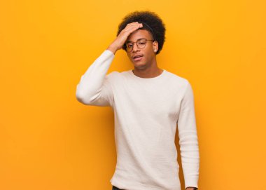 Turuncu bir duvar üzerinde genç afrikalı Amerikalı adam yorgun ve çok uykulu