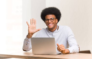 Beş numarayı gösteren dizüstü bilgisayarını kullanan genç siyah adam