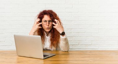 Dizüstü bilgisayarıyla çalışan genç kızıl saçlı kıvırcık kadın gergin elleriyle çığlık atıyordu.