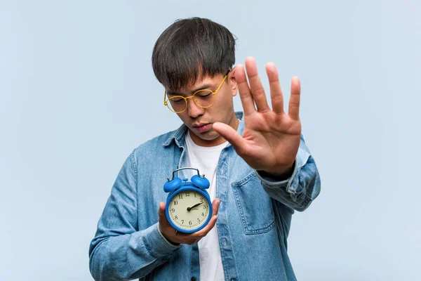 Young Chinese Man Holding Alarm Clock Putting Hand Front — Stock Photo, Image