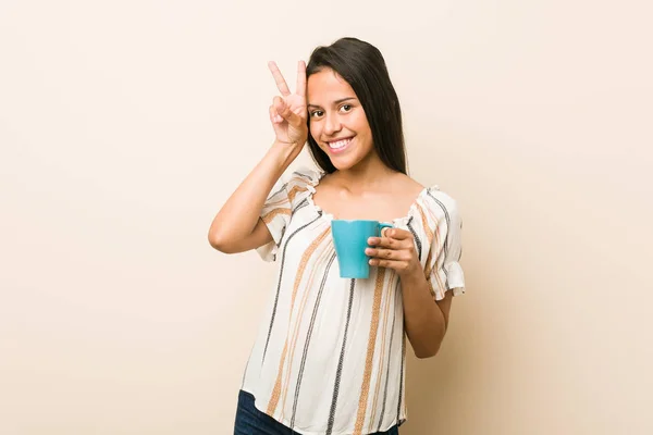 Junge Hispanische Frau Hält Eine Tasse Mit Siegeszeichen Und Lächelt — Stockfoto