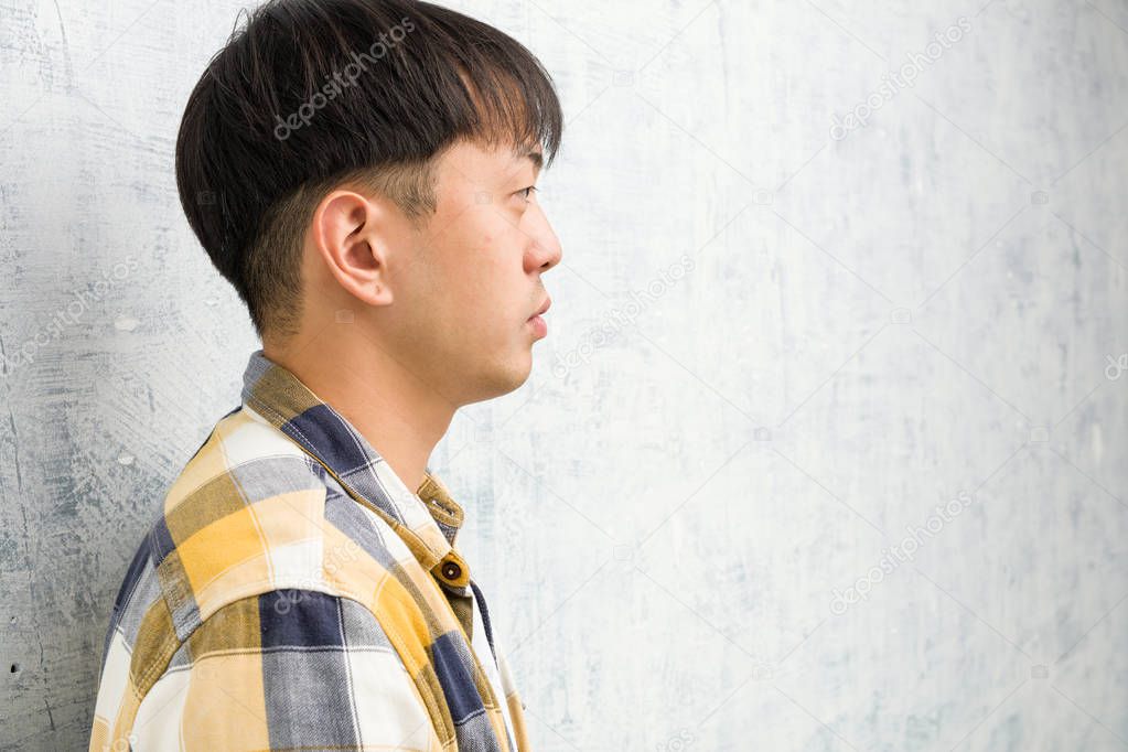 Young chinese man face closeup on the side looking to front