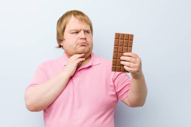 Beyaz çılgın sarışın şişman adam bir çikolata tablet tutan