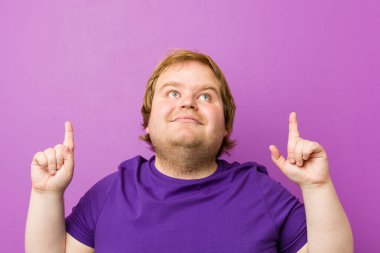 Genç otantik kızıl saçlı şişman adam boş bir boşluk gösteren kadar her iki ön parmak ile gösterir.