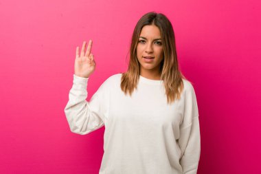 Bir duvara karşı genç otantik karizmatik gerçek insanlar kadın neşeli ve kendinden emin ok jest gösteren.