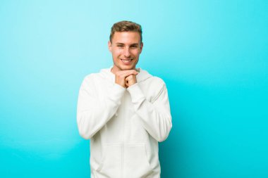 Genç kafkas spor adam çene altında ellerini tutar, bir kenara mutlu bakıyor.