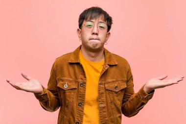 Genç Çinli adam bir ceket giyen şaşkın ve şüpheli