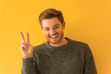 Genç kızıl saçlı adam zafer jesti yaparak yakın çekim yüz