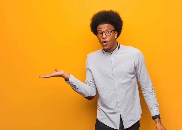 Young African American Man Orange Wall Holding Something Palm Hand — Stock Photo, Image