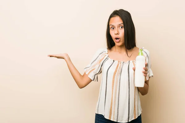 Junge Hispanische Frau Mit Einer Cremeflasche Beeindruckt Hält Kopierraum Auf — Stockfoto