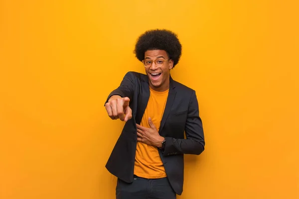 Young business african american man over an orange wall dreams of achieving goals and purposes