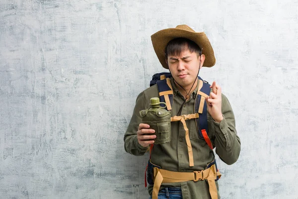 Young explorer chinese man crossing fingers for having luck