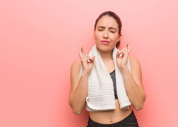 Young fitness woman crossing fingers for having luck