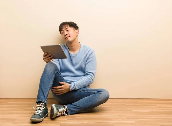 目標と目的を達成することを夢見てタブレットを使用して座っている若い中国人男性 — ストック写真