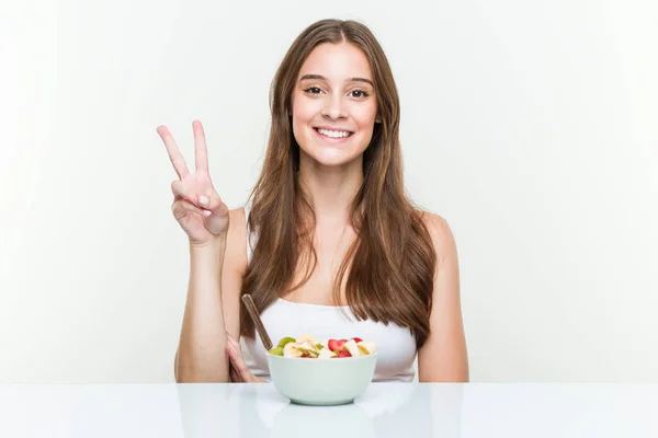 Mujer Joven Caucásica Comiendo Frutero Mostrando Número Dos Con Los — Foto de Stock