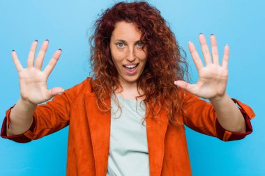 Genç kızıl saçlı zarif kadın elleri ile on numara gösteren.