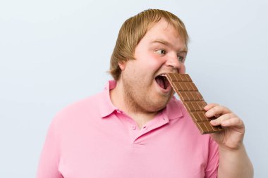 Beyaz çılgın sarışın şişman adam bir çikolata tablet tutan