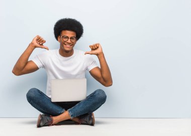 Genç siyah adam parmakları işaret eden bir dizüstü bilgisayar ile katta oturan, örnek takip etmek