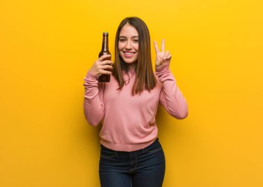 Genç sevimli kadın iki numara gösteren bir bira tutan