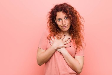 Genç doğal ve otantik kızıl saçlı kadın samimi bir ifade vardır, göğüs palmiye basarak. Aşk kavramı.