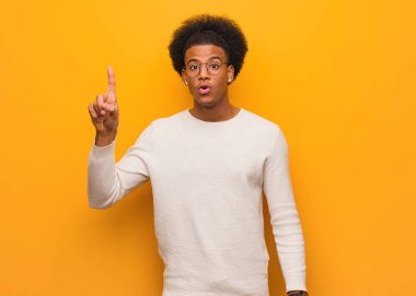 Turuncu bir duvarın üzerinde genç afro-amerikan adam harika bir fikir, yaratıcılık kavramı olan