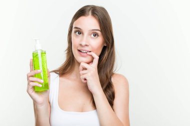 Aloe vera şişesi tutan genç beyaz kadın bir kopya alanına bakan bir şey hakkında düşünerek rahatladı.
