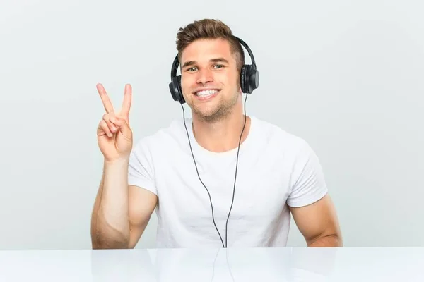 Mladý Muž Poslouchá Hudbu Sluchátky Zobrazující Číslo Dvě Prsty — Stock fotografie