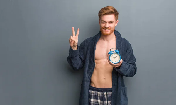 Jeune Homme Rousse Pyjama Montrant Numéro Deux Tient Réveil — Photo