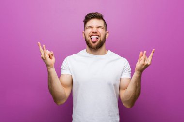 Genç yakışıklı beyaz adam parmakları ile kaya jesti gösteren