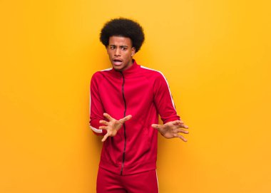 Bir şey iğrenme bir jest yapıyor reddeden turuncu bir duvar üzerinde genç spor siyah adam