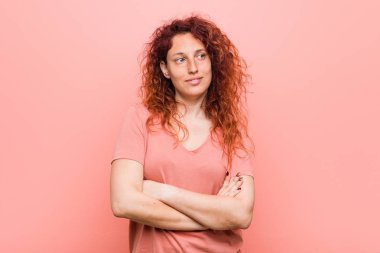 Genç doğal ve otantik kızıl saçlı kadın çapraz kolları ile emin gülümseyen.