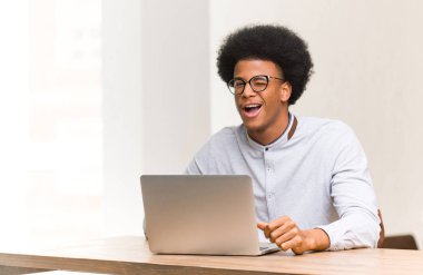 Genç siyah adam onun laptop göz kırpma kullanarak, komik, samimi ve kaygısız jest