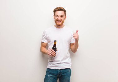 Genç kızıl saçlı adam gülümsüyor ve başparmağını kaldırıyor. Birbira tutmak.