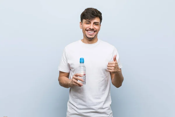 Jonge Spaanse Man Houdt Een Waterfles Glimlachend Omhoog Duim Omhoog — Stockfoto